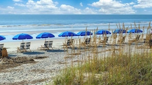 Una playa con sombrillas azules y sillas de descanso.