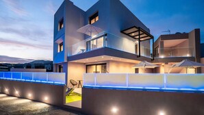 A modern multi-story building with a balcony, outdoor seating area, and a pool. - Elixir Villa 7BD 4BD 14PL - 3min walk to the beach (Georgioupoli)