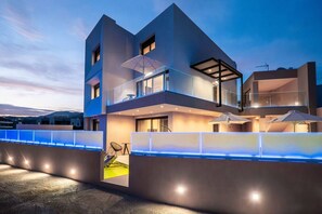 Ein modernes Mehrfamilienhaus mit Balkon, Sitzbereich im Freien und einem Pool.