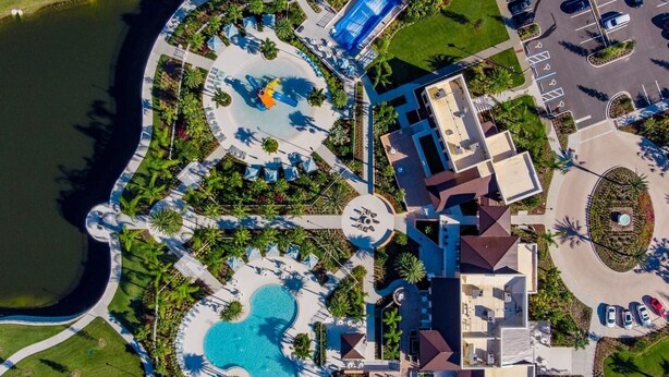 An aerial view of a resort with a central pool, multiple guest rooms, and a parking area. - 6BR/5BA Luxurious with Private Pool (Kissimmee)