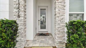 Une maison blanche avec une façade en pierre et le numéro « 1728 » inscrit sur le pilier de gauche.