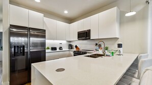 Une cuisine moderne avec des meubles blancs, des appareils en acier inoxydable et un îlot central.