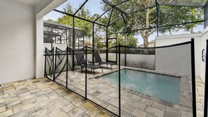 Une piscine extérieure couverte, dotée d’une structure en verre, d’un revêtement de sol en pierre et de quelques chaises longues.