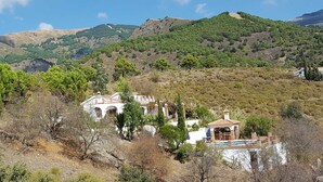 A rural setting with a white building featuring arches and a smaller structure with a tiled roof. - Villa Los Almendros (Canillas de Albaida)