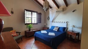 A bedroom with a bed, bedside tables, a lamp, a window, and a hanging light fixture. - Villa Los Almendros (Canillas de Albaida)