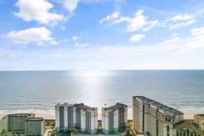 A beachfront hotel with multiple high-rise buildings, a clear sky, and a calm sea.