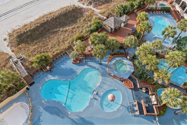 Un resort con múltiples piscinas, zonas de descanso y palmeras.
