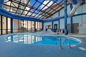 Una piscina interior con agua cristalina azul, rodeada de paredes azules y un techo de cristal.