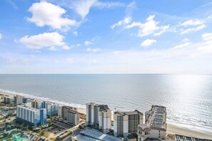 A coastal cityscape with high-rise buildings, a beach, and a clear sky. - Cozy Oceanview at Beach Cove (North Myrtle Beach)
