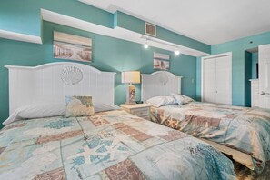 Un dormitorio con dos camas, una mesita de noche con lámpara y una puerta.