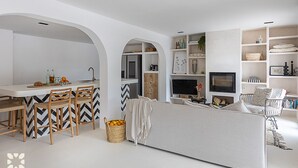 Una sala de estar moderna con un sofá, un comedor con sillas y una cocina visible a través de un arco.