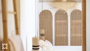 Una habitación con un ventanal grande con tres paneles arqueados y texturas tejidas.