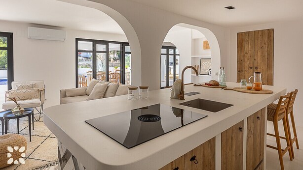 Una cocina moderna con una isla central, dos fregaderos y armarios de madera.