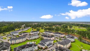 Bairro residencial com várias casas de dois andares, piscina e campo de golfe ao fundo.