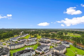 A residential area with multiple two-story houses, a swimming pool, and a golf course in the background.