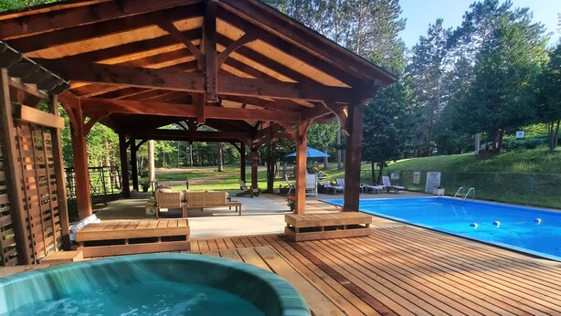 Una terraza de madera con un jacuzzi y una piscina.