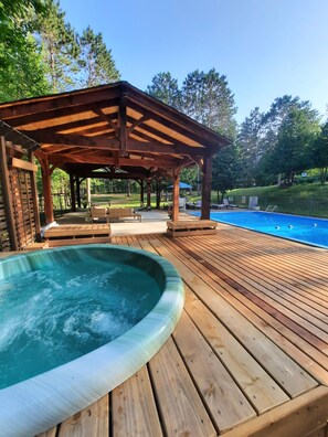Una terraza de madera con un jacuzzi y una piscina.