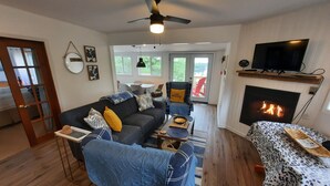 Una sala de estar con sofá, mesa de centro, chimenea y televisor.