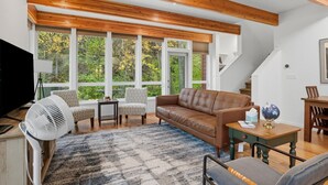 A living room with a brown leather sofa, patterned armchairs, a white fan, and a blue patterned rug. - Creekside 3BR Retreat Near Downtown, Airport & Fish Creek (Anchorage)