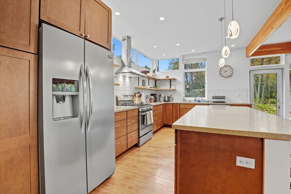 A modern kitchen with stainless steel appliances, wooden cabinets, and a large island.