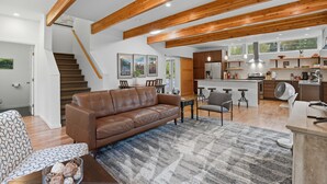 A spacious living area with a brown leather sofa, a dining table, and a kitchen in the background. - Creekside 3BR Retreat Near Downtown, Airport & Fish Creek (Anchorage)