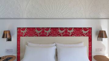 Ein Hotelzimmer mit einem Bett, zwei Nachttischlampen, einem Nachttisch und einer Wand mit floralem Muster.