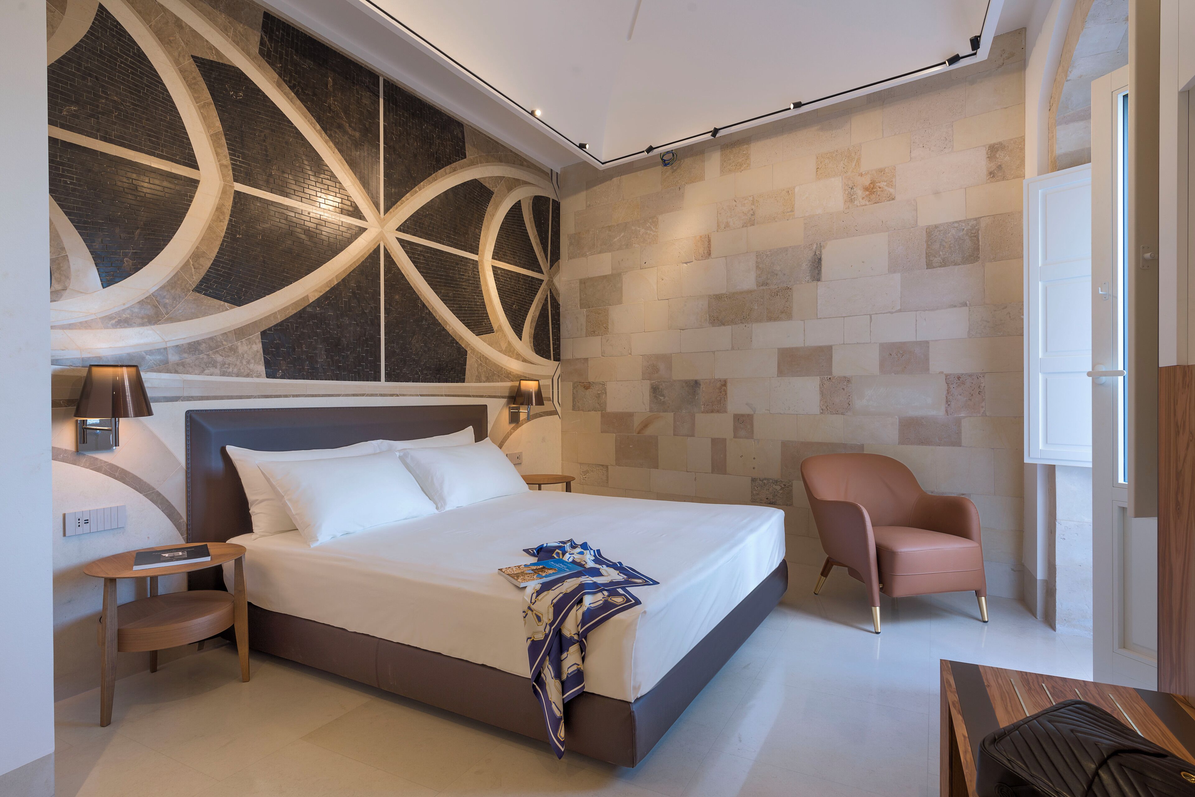 Una habitación de hotel moderna con una cama grande, un rincón de descanso con una silla y una mesita.