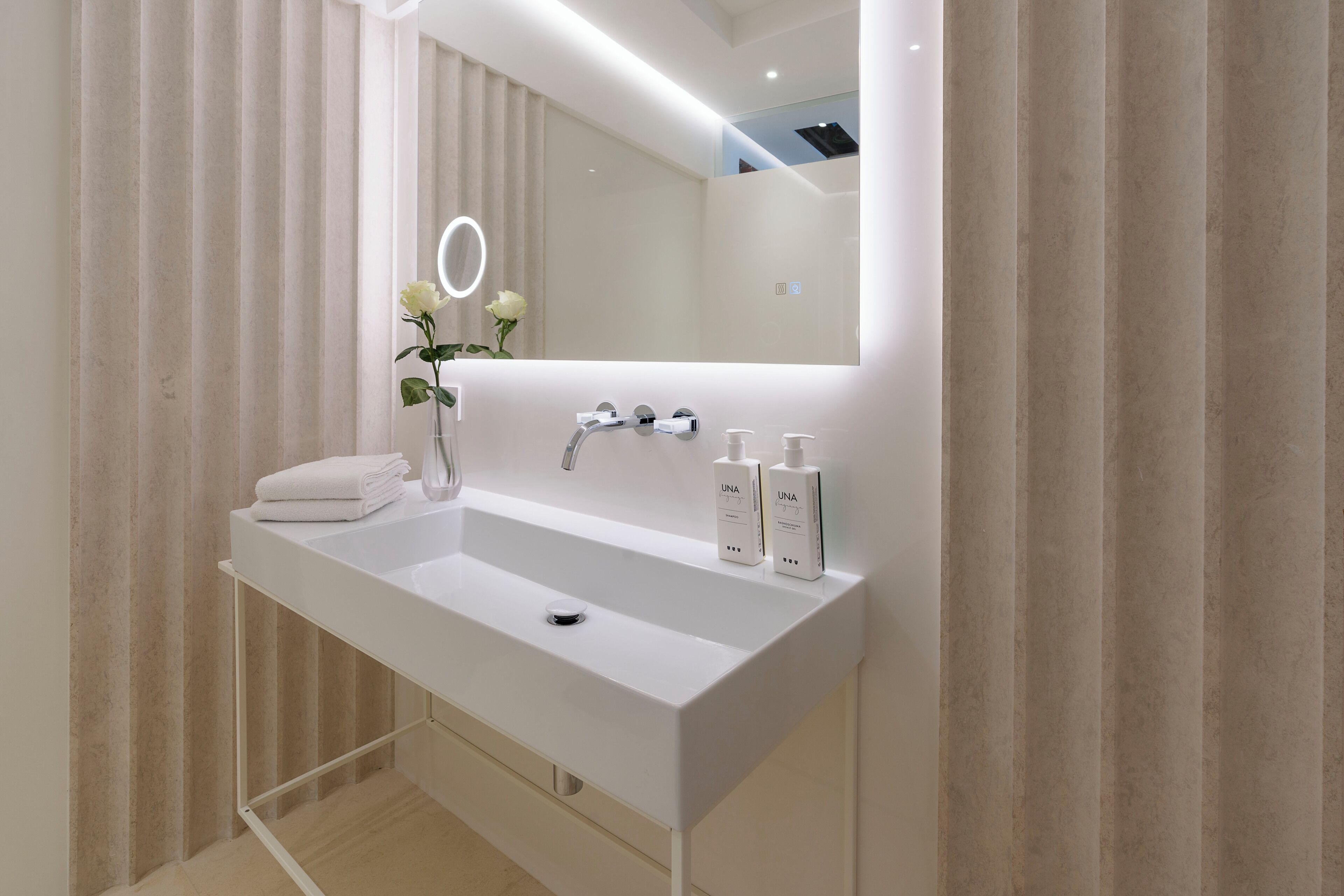 Une salle de bain moderne avec un lavabo blanc, un miroir et un anneau lumineux placé au-dessus du miroir.