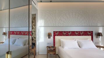 Een moderne hotelkamer met een groot bed, een klein nachtkastje, een spiegel en een decoratief hoofdbord.