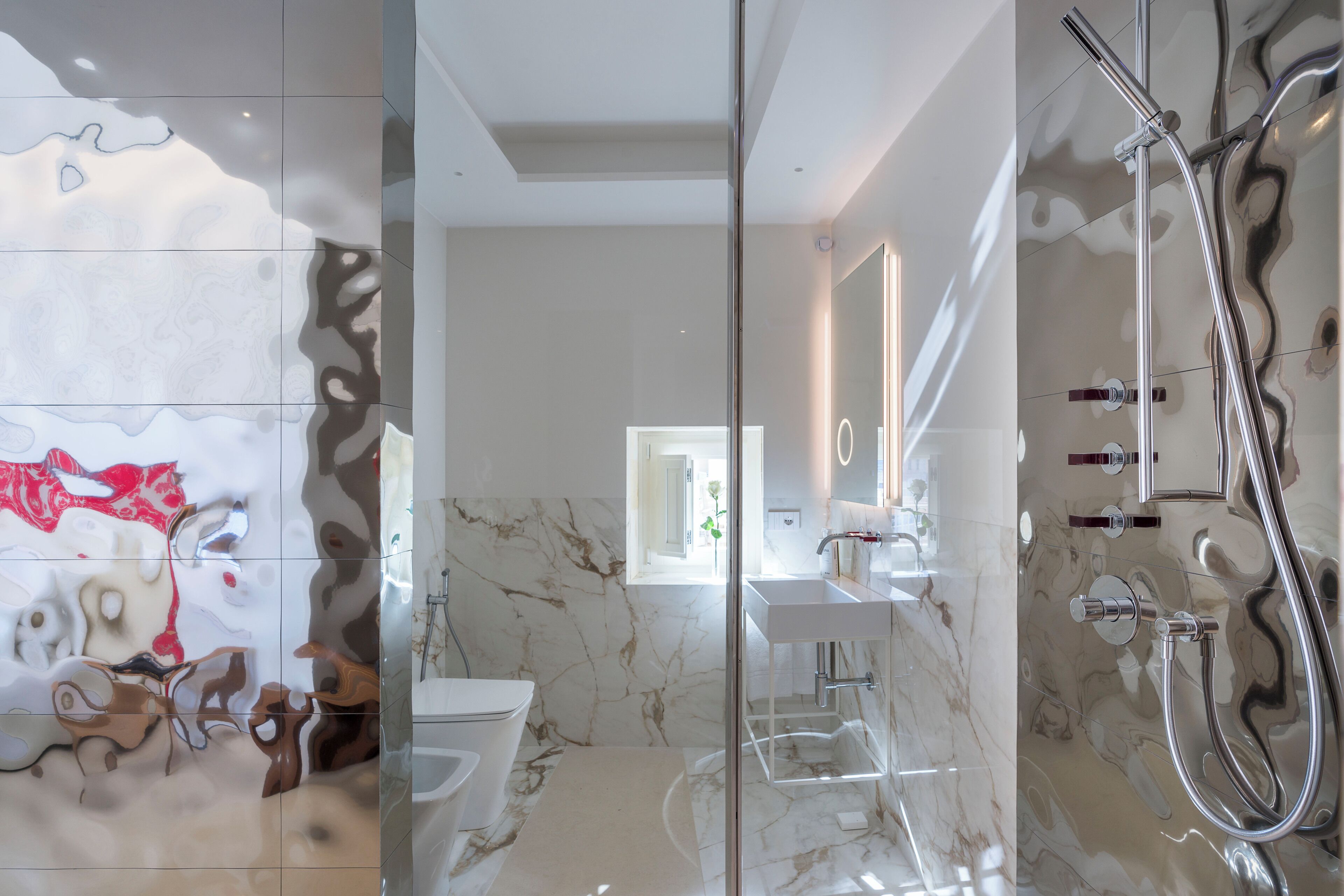 Un bagno moderno con cabina doccia in vetro, pavimento in marmo e lavabo bianco.