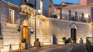 A historic building with a stone facade, a balcony with a wrought iron railing, and a parked motorcycle. - Maniace Boutique Hotel Ortigia UNA Esperienze (Syracuse)