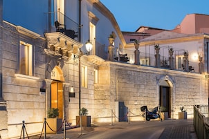 A historic building with a stone facade, a balcony with a wrought iron railing, and a parked motorcycle.