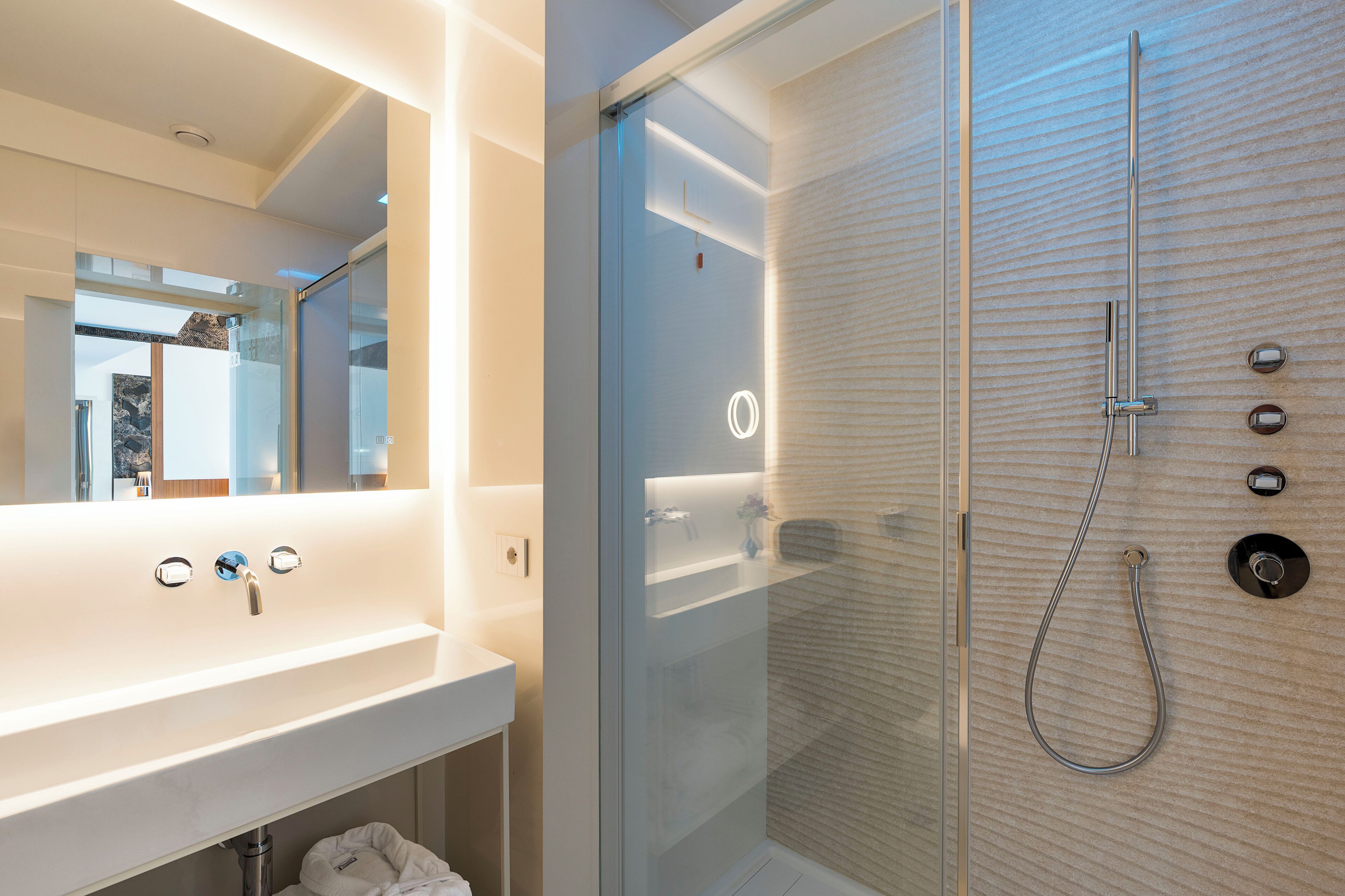 Een moderne badkamer met een douche met glazen wand, een wit wastafelmeubel en een spiegel.