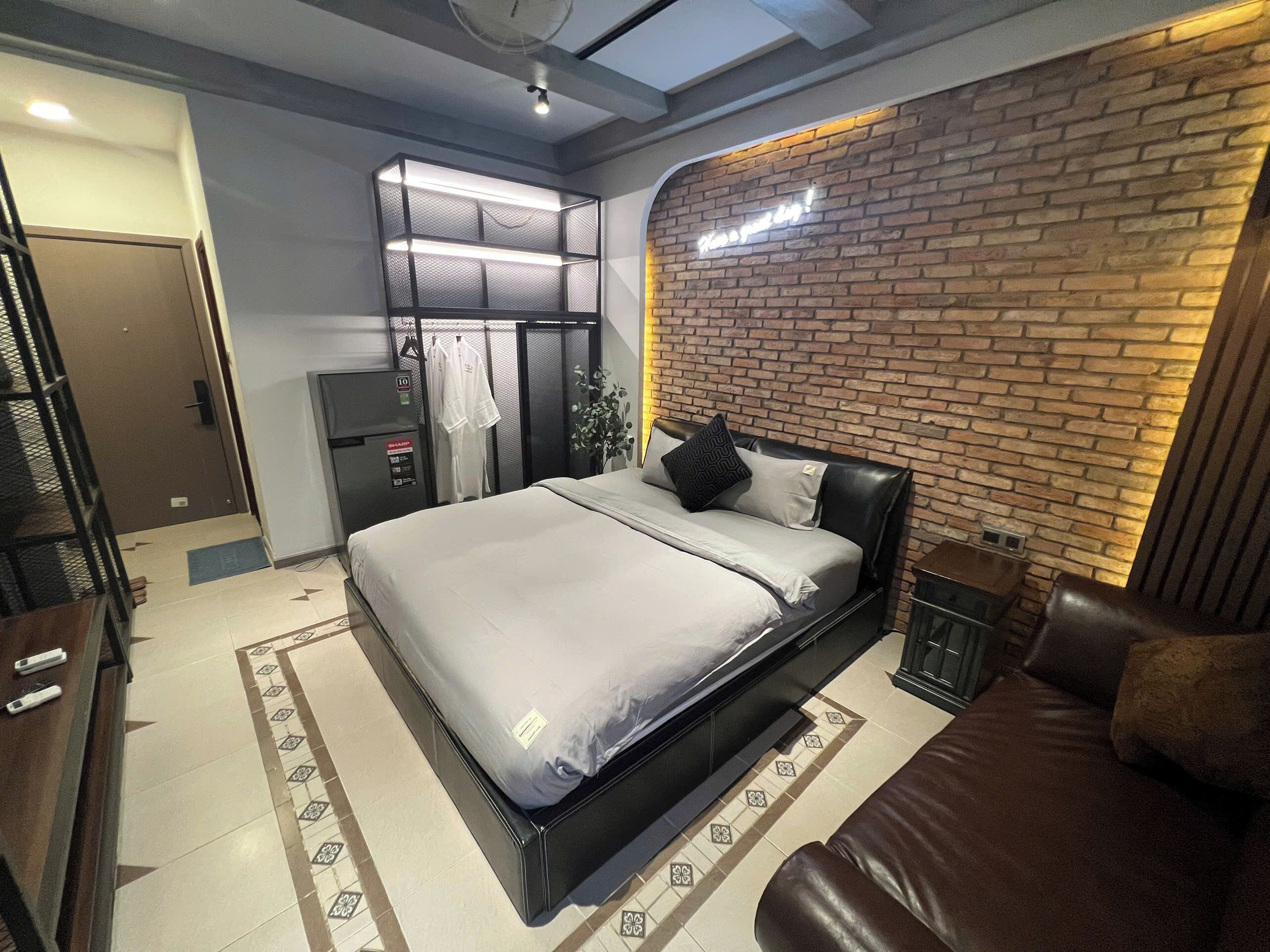 A modern bedroom with a bed, a chest of drawers, a wardrobe, and a brick accent wall.