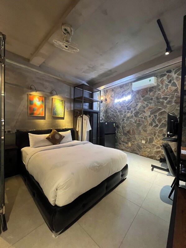Un dormitorio moderno con una cama grande, una pared de piedra y un ventilador de techo.