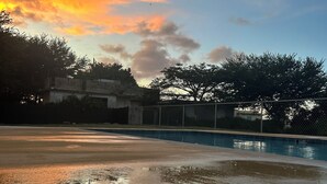 A swimming pool with a fence, trees, and buildings in the background. - 4-bedroom oasis in amazing Hatillo (Barrio pueblo)
