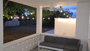 A covered outdoor seating area with a sofa and a coffee table, string lights, and a ceiling fan. - 4-bedroom oasis in amazing Hatillo (Barrio pueblo)