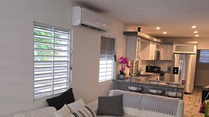 A modern living room with a sofa, ottoman, and a remote control on the ottoman. - 4-bedroom oasis in amazing Hatillo (Barrio pueblo)