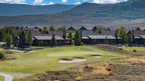 Een lodge met verschillende bungalows, een golfbaan en een bergachtig achtergrond.