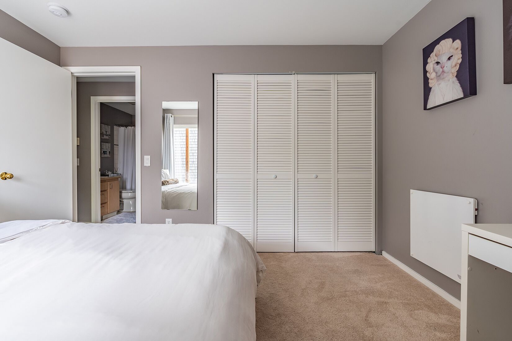 A bedroom with a bed, a wardrobe, a mirror, and a radiator.