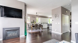 A modern living room with a fireplace, dining area, and kitchen. - Majestic Views with a Hot Tub! (Seattle)