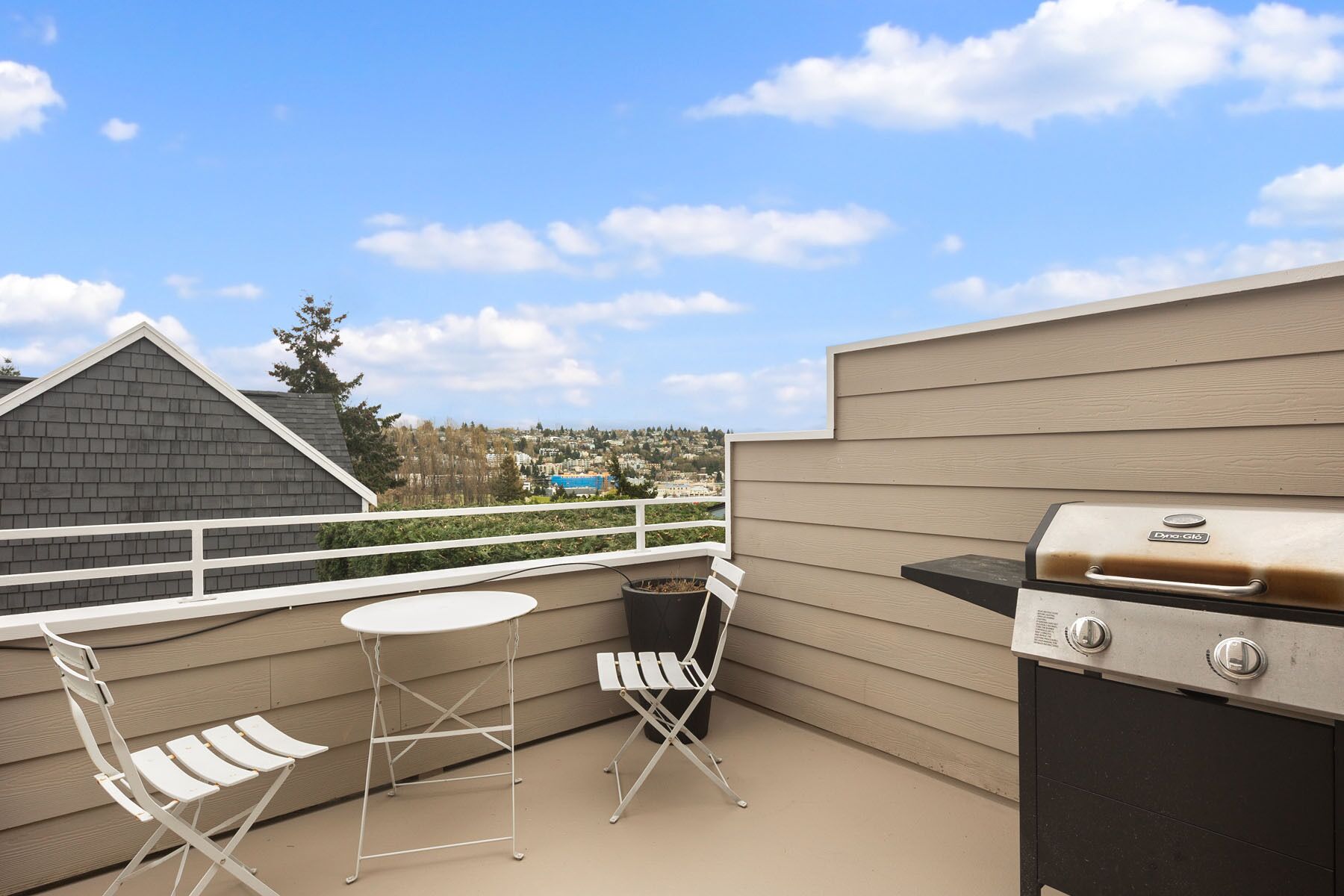 A balcony with a grill, a small table, and two chairs.