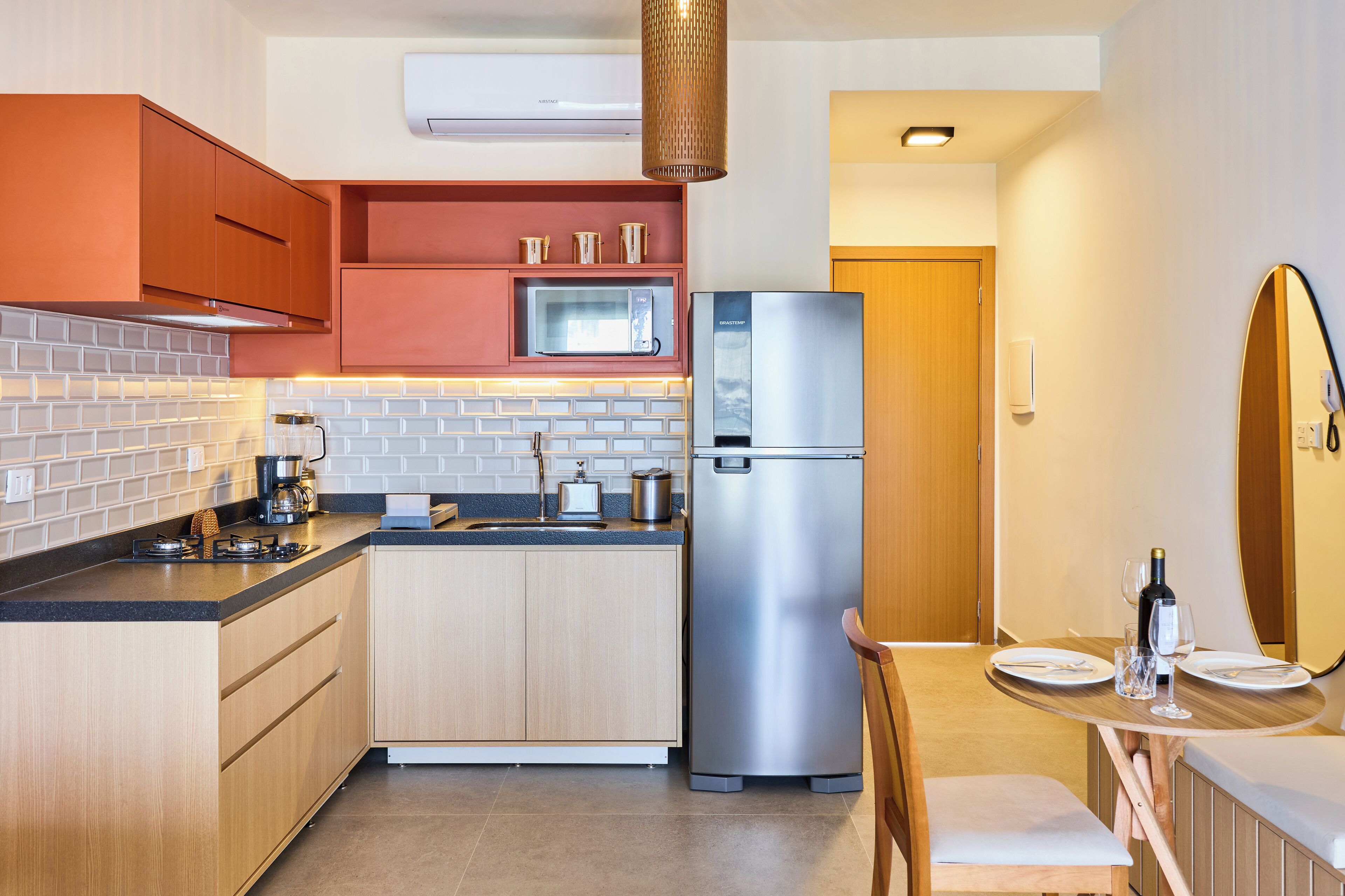 A compact kitchen with a microwave, refrigerator, and a dining area with a table and chairs.