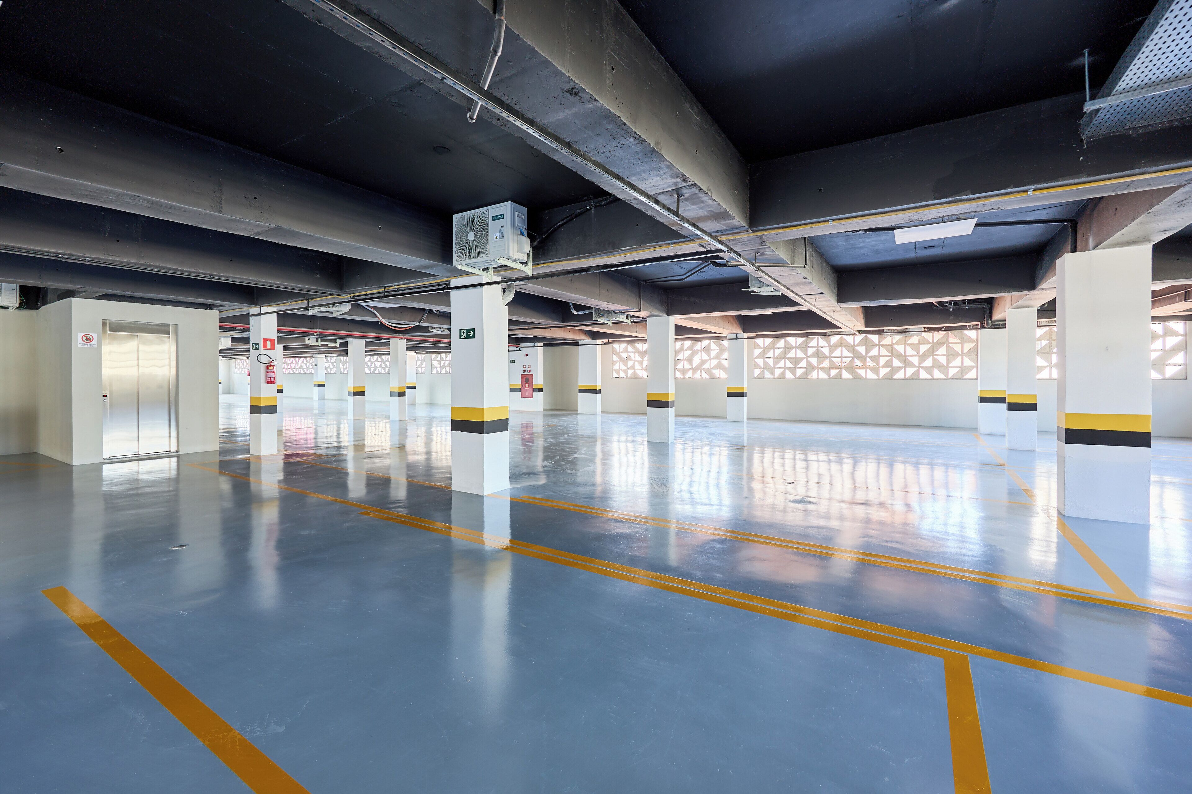 An empty parking garage with concrete pillars, yellow lines, and a clean floor.