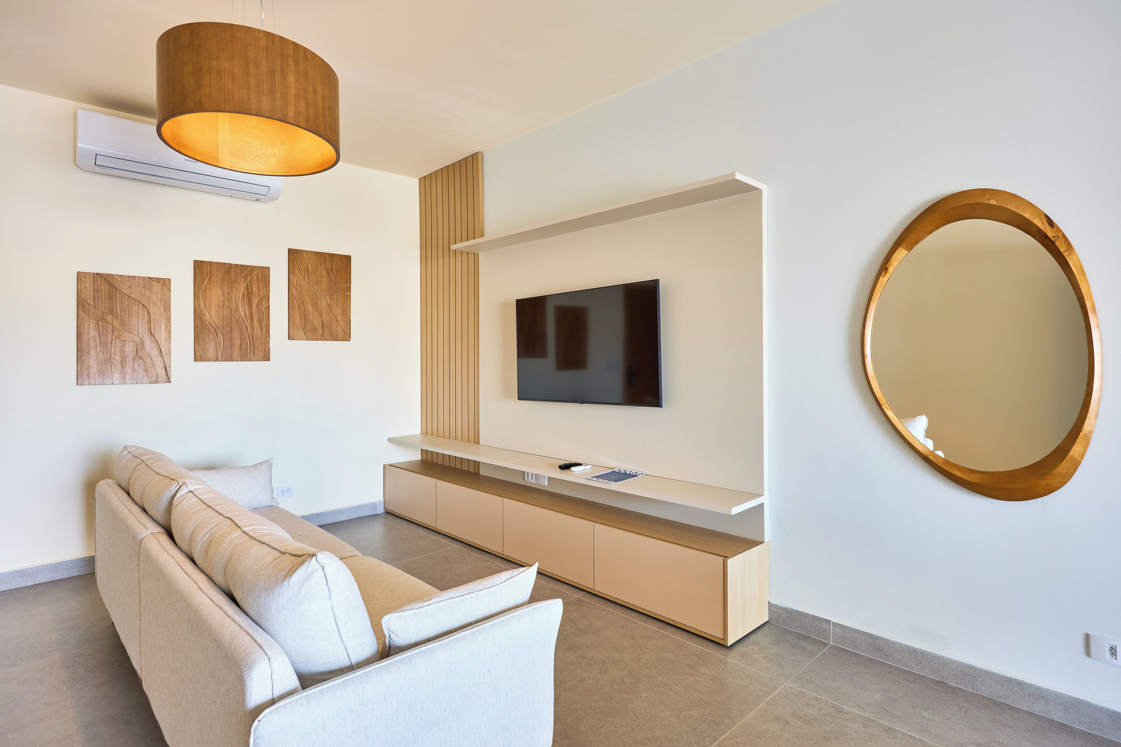 Una sala de estar moderna con un sofá, televisor y un espejo grande.
