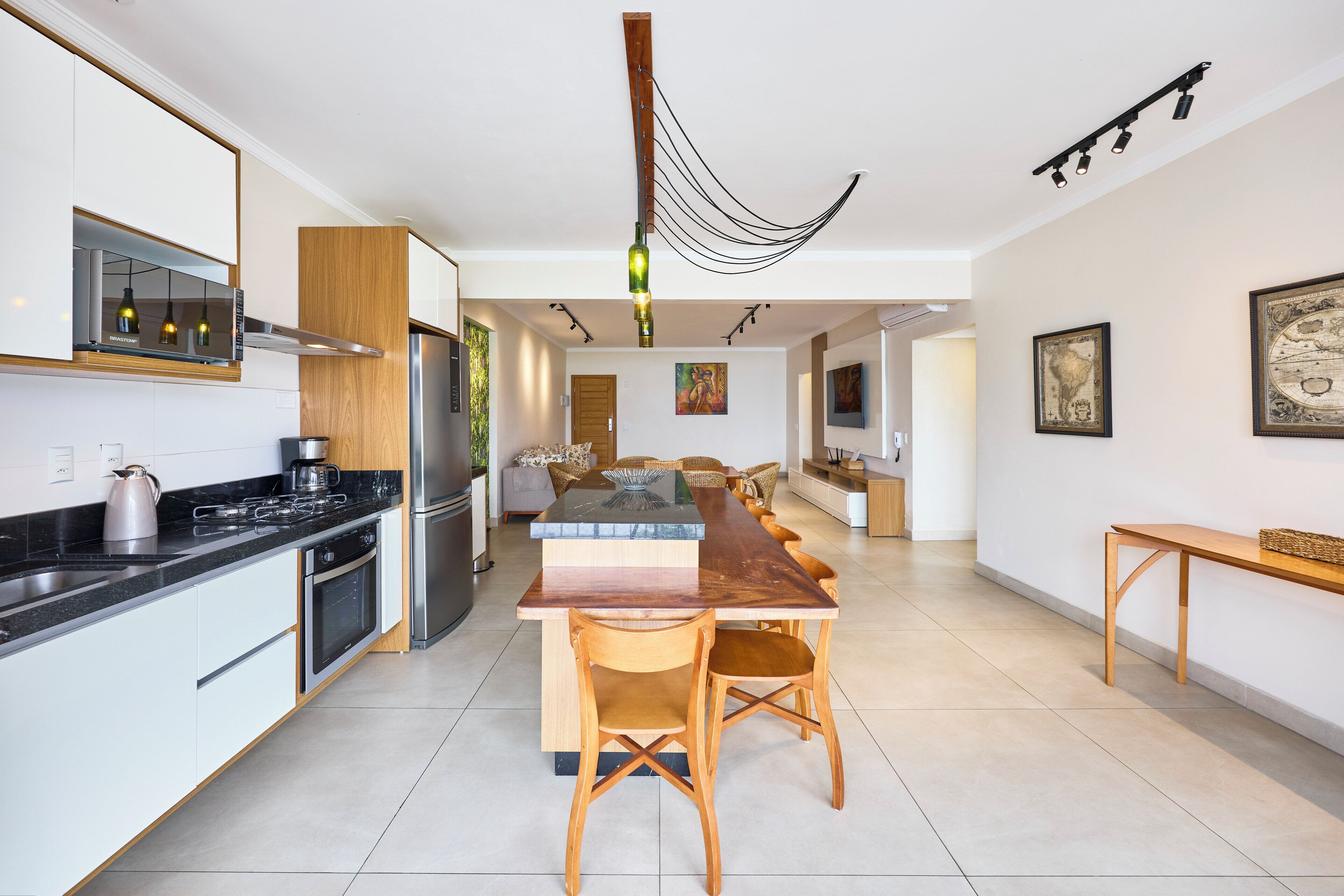 Uma cozinha moderna com ilha central, eletrodomésticos de aço inoxidável e iluminação pendente.