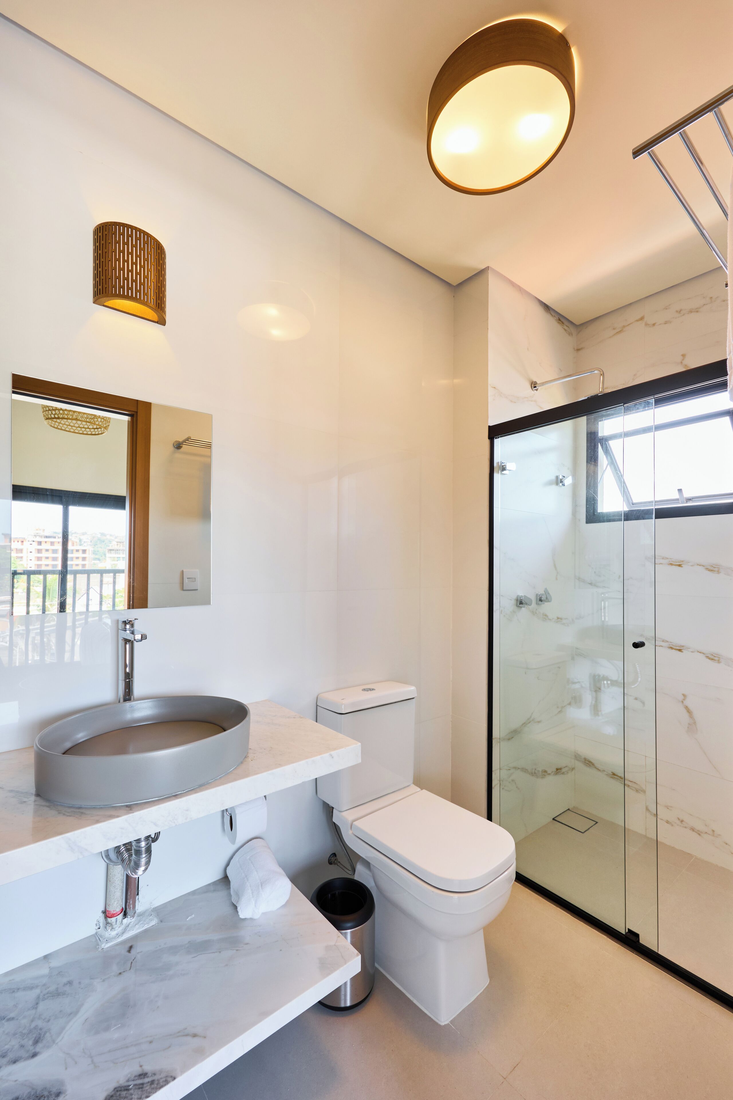 A modern bathroom with a marble sink, toilet, and a glass-enclosed shower.