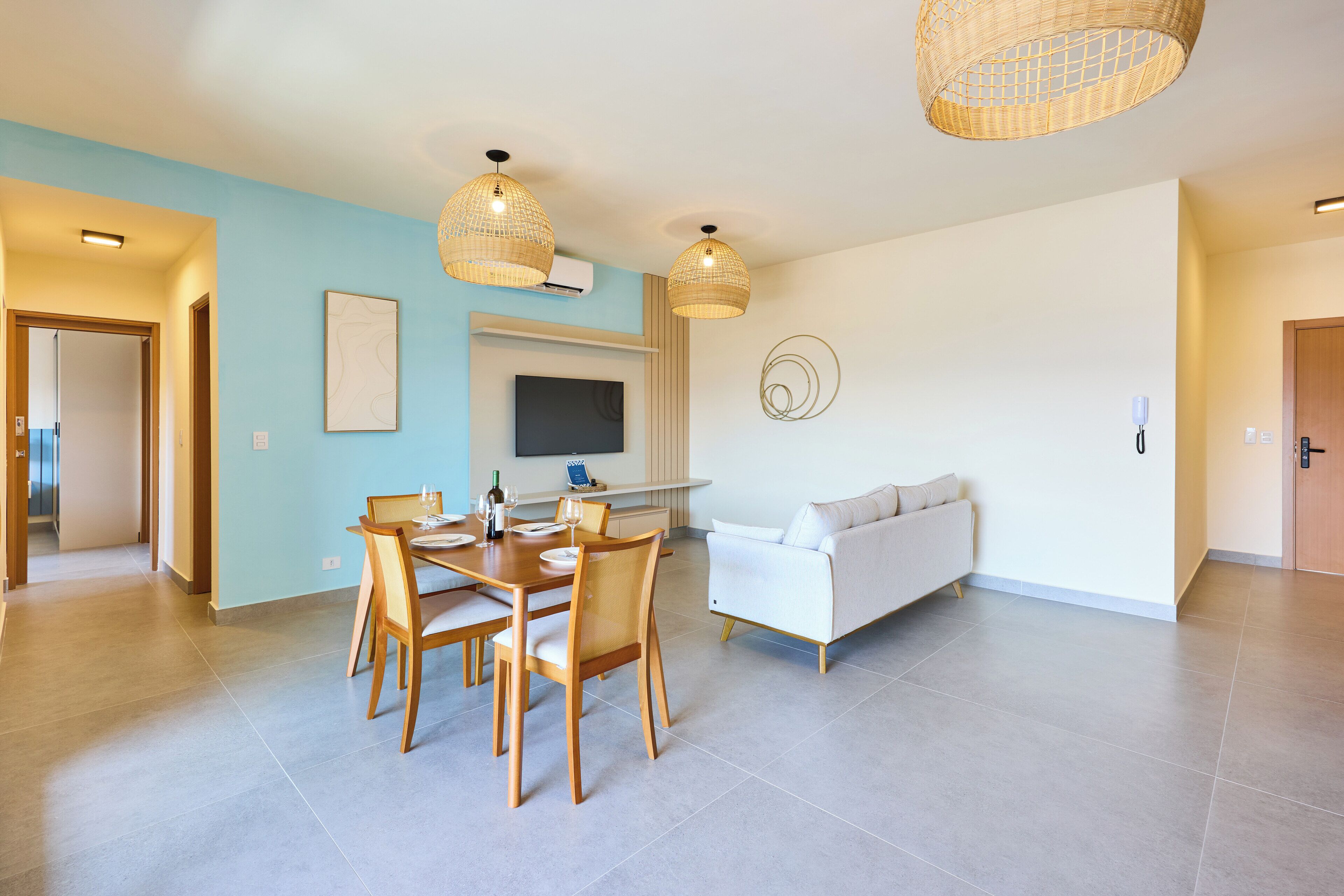 A modern living room with a dining area, a sofa, and a flat-screen TV.