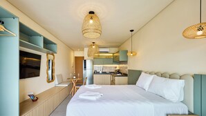 Habitació d'hotel moderna amb un llit gran, una cuineta petita, una zona de menjador i un televisor.