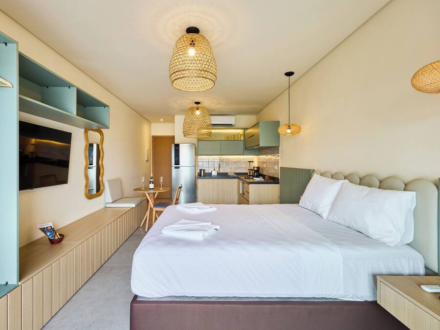 Una habitación de hotel moderna con una cama grande, una kitchenette pequeña, un comedor y un televisor.